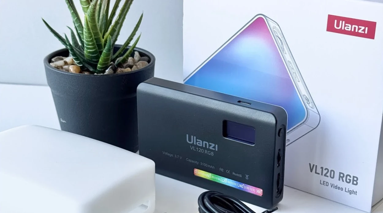Чорна панель Ulanzi VL120 RGB поруч із фірмовим силіконовим розсіювачем, коробкою та кабелем живлення на світлій поверхні столу